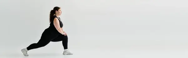 A stylish plus size woman engages in a lunge exercise, showcasing strength and grace. — Stock Photo