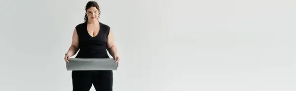 A graceful plus size woman stands confidently, holding a textured garment, embodying elegance. — Stock Photo