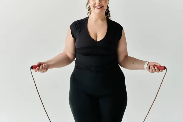 Una bella donna plus size salta felicemente con una corda di salto, trasudando fiducia e grazia. — Foto stock