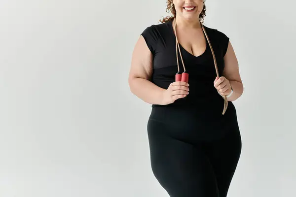 Une femme confiante et élégante se tient avec une corde à sauter, mettant en valeur son voyage de remise en forme et son élégance. — Photo de stock