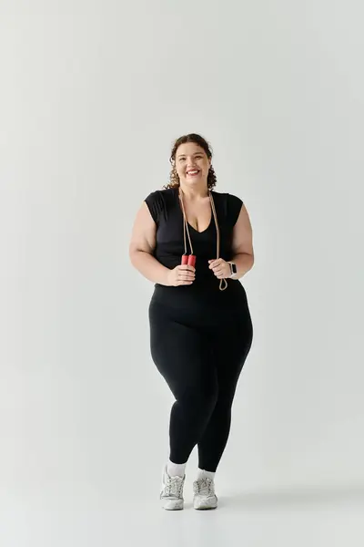 A joyful plus size woman engages in an energetic workout, smiling brightly while skipping rope. — Stock Photo
