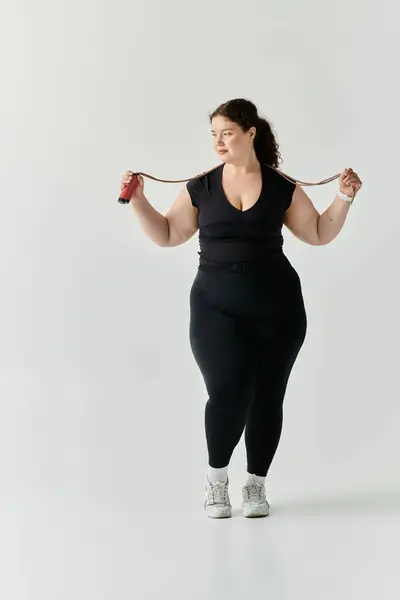 A graceful plus size woman poses with a jump rope, exuding confidence and strength. — Stock Photo