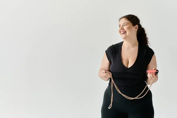A graceful plus size woman smiles while holding a jump rope, radiating confidence and positivity. — Stock Photo