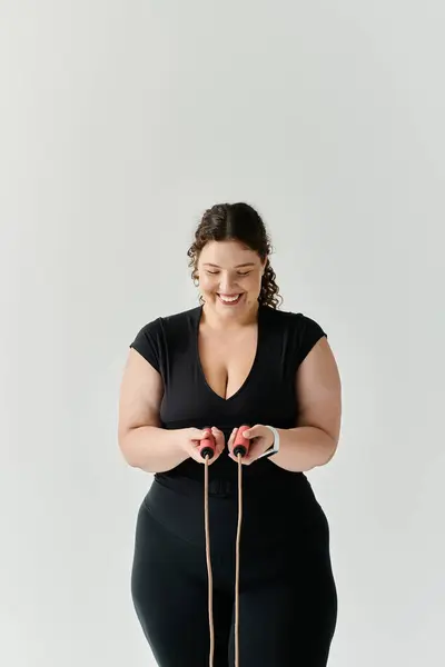 A graceful plus size woman smiles while holding a jump rope, ready for her fitness routine. — Stock Photo