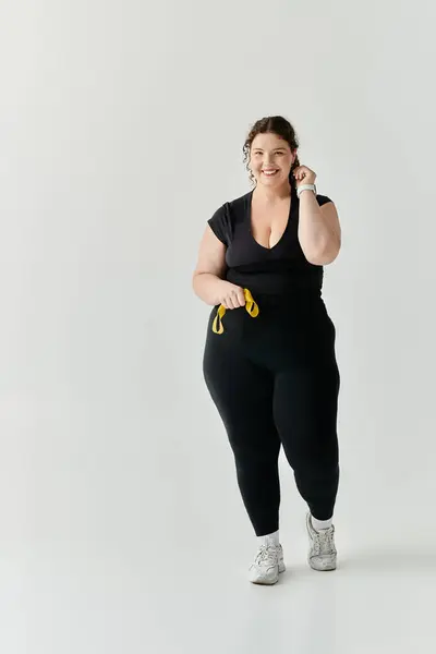 A beautiful, confident plus size woman smiles brightly while engaging in a light workout indoors. — Stock Photo