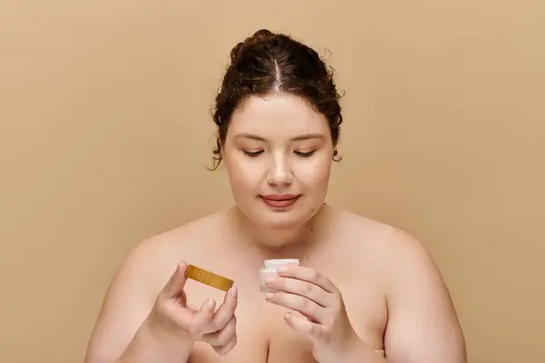 A graceful woman examines her skincare products, embracing self care with serenity and joy. — Stock Photo