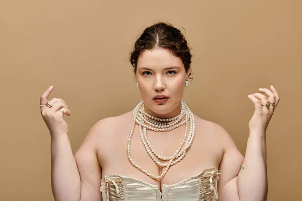 Une femme élégante plus la taille met en valeur l'élégance avec des perles, frappant une pose confiante dans un studio. — Photo de stock