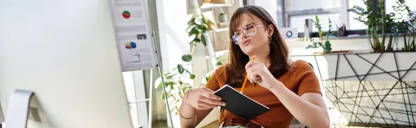 A non binary individual sits pensively in a modern office, jotting notes while immersed in thought. — Stock Photo