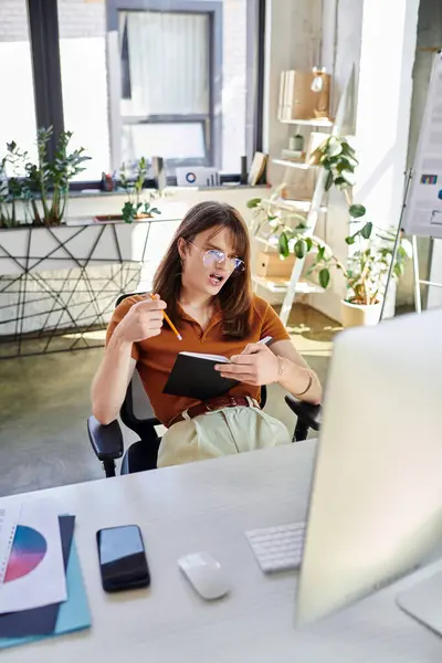 Eine junge, nicht binäre Person sitzt an einem stilvollen Schreibtisch und denkt über Ideen nach.. — Stockfoto