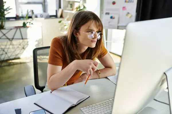 Concentrated individual engages with their computer, taking notes and brainstorming ideas. — Stock Photo