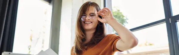 La luz del sol brillante ilumina a la persona alegre no binaria mientras se dedican a tareas de oficina. - foto de stock