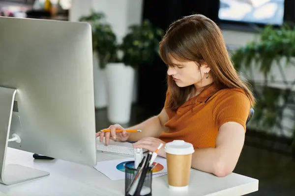 Focused individual in a vibrant office thoughtfully creates designs while sipping coffee. — Stock Photo