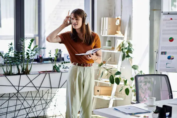 Engaged in a song, a young non binary individual sways while taking notes in a stylish workspace. — Stock Photo