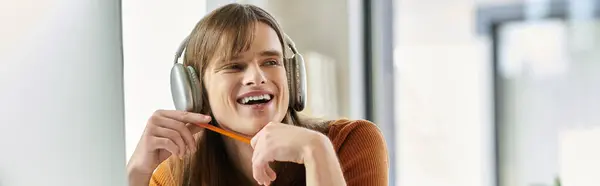 This young non binary individual smiles and holds a pencil while immersed in their work. — Stock Photo