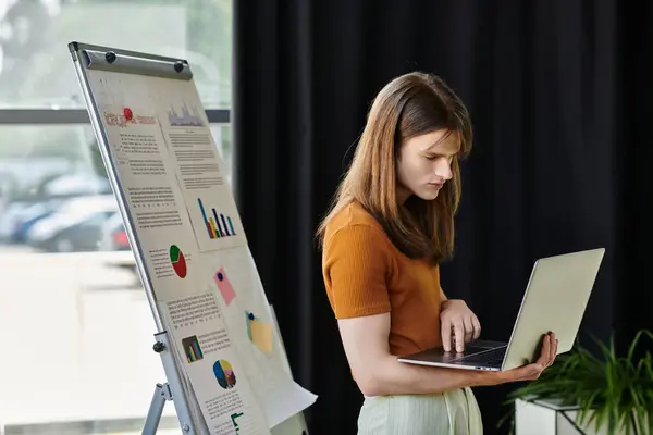 The individual focuses intently on their laptop while surrounded by visual data displays. — Stock Photo