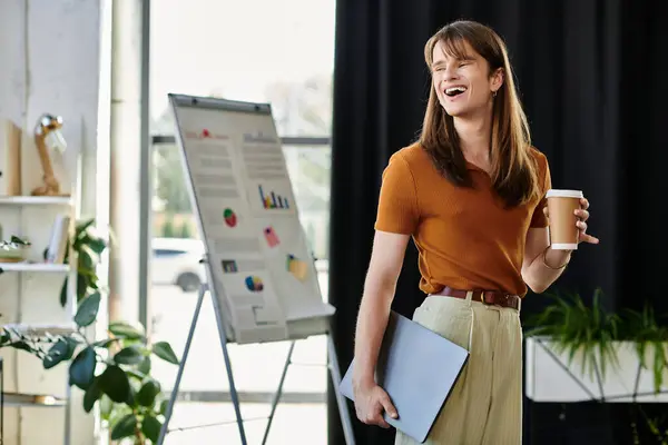 In a lively office environment, a young non binary individual shares ideas while smiling. — Stock Photo