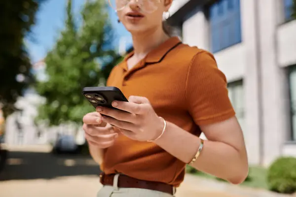An individual engages with their smartphone while surrounded by greenery and modern architecture. — Stock Photo