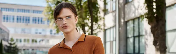 A young non binary person stands in an office, exuding confidence amidst lush greenery outside. — Stock Photo