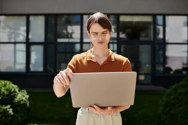 The young non binary individual is engaged in work on their laptop in a bright outdoor office. — Stock Photo