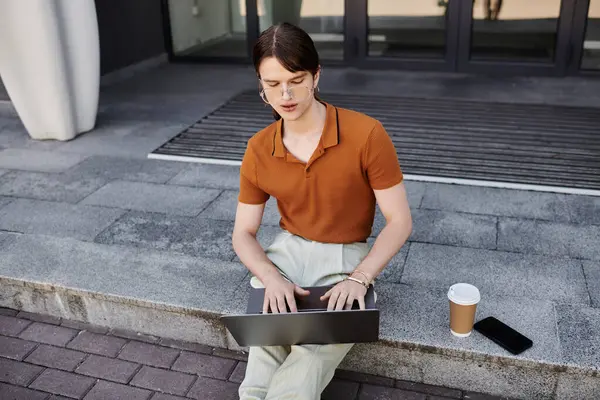 Attentively typing on a laptop while seated outside with coffee nearby, enjoying the workspace. — Stock Photo