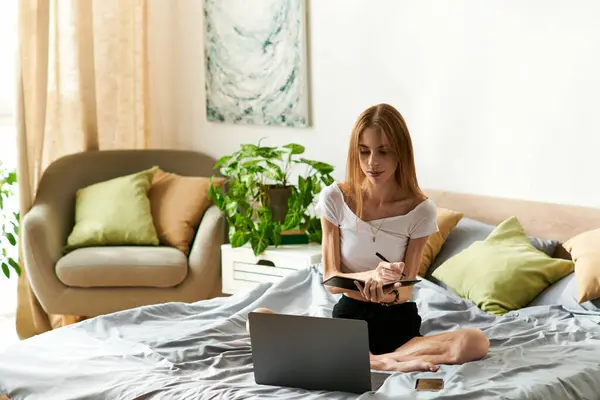 Una giovane donna si siede comodamente a casa, scrivendo nel suo diario, sentendosi in pace e felice nel suo spazio accogliente. — Foto stock