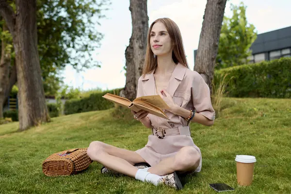 A young woman with anorexia sits cross-legged on the grass, immersed in her book, radiating happiness on a sunny day. — Stock Photo