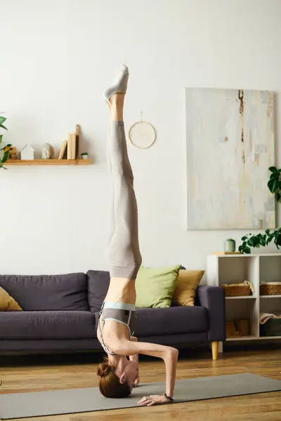 A determined young woman with anorexia showcases her strength and focus while practicing handstands in her cozy living space. — Stock Photo