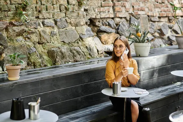 Una joven se sienta cómodamente en un acogedor café, bebiendo su bebida y abrazando su viaje único con confianza. - foto de stock