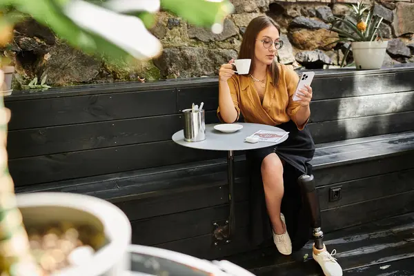 Uma jovem relaxa em um café encantador, tomando café e verificando seu smartphone enquanto abraça sua rotina diária. — Fotografia de Stock