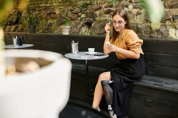 In a cozy cafe, a young woman with a prosthetic leg savors her coffee, embracing her vibrant lifestyle while relaxing. — Stock Photo