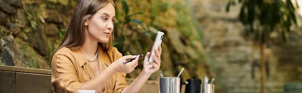 A young woman sits in a cozy cafe, engaged in her smartphone while savoring the ambiance. — Stock Photo