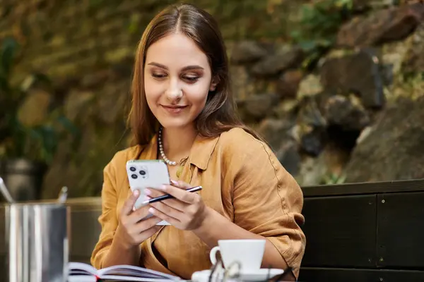 Une jeune femme, confortablement assise dans un café confortable, s'engage avec son téléphone — Photo de stock