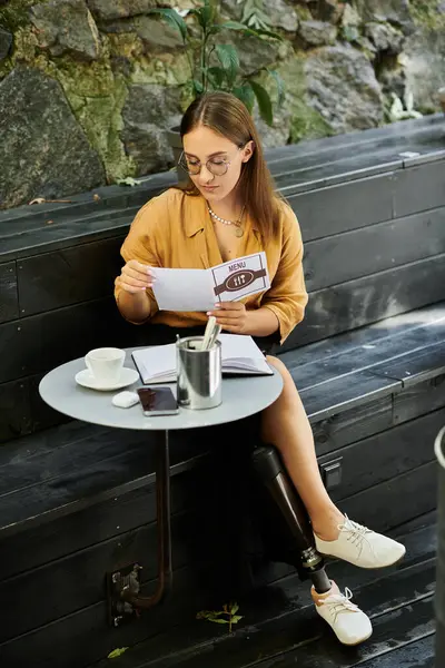 A young woman sits comfortably in a cafe, reviewing documents while embracing her daily life with style and positivity. — Stock Photo