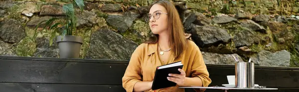 A young woman sits comfortably in a cafe, absorbed in her notebook, enjoying the atmosphere. — Stock Photo