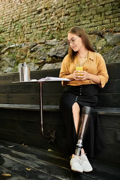 A young woman sits comfortably in a charming cafe, savoring her drink while showcasing her vibrant lifestyle with a prosthetic leg. — Stock Photo