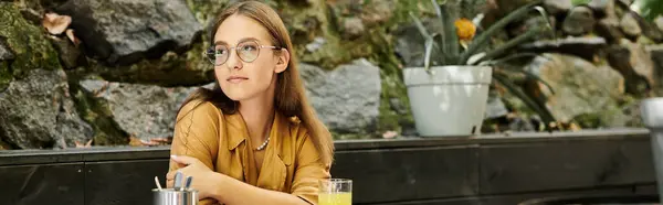 In a vibrant cafe, a young woman with a prosthetic leg relaxes, savoring her drink while enjoying the atmosphere. — Stock Photo