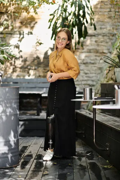 In a charming cafe, a young woman with a prosthetic leg smiles while savoring her moment, embodying resilience and joy. — Stock Photo