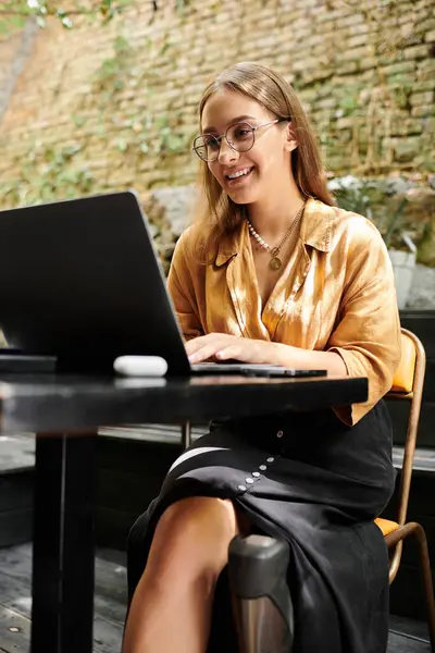 In a cozy cafe, a young woman with a prosthetic leg smiles as she focuses on her laptop, embracing her vibrant lifestyle. — Stock Photo