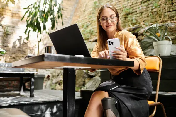 Sentado confortavelmente em um café, uma jovem mulher com uma perna protética se engaja com seu smartphone, abraçando a vida cotidiana.. — Fotografia de Stock