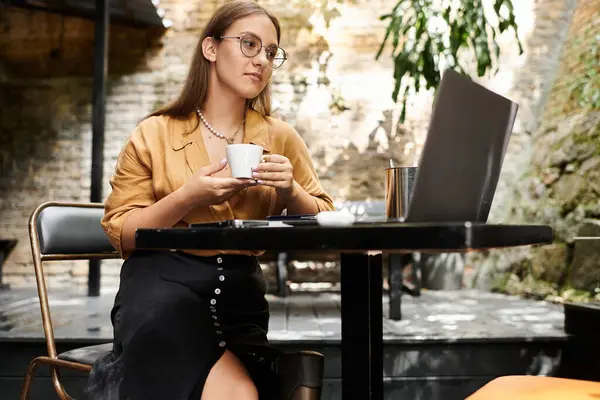 En un ambiente cálido café, una joven con una extremidad artificial saborea su café, encarnando la resiliencia y el estilo. — Stock Photo