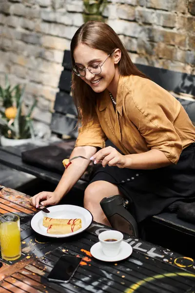 Una joven con un miembro artificial sonríe mientras disfruta del brunch en un café, abrazando su estilo de vida diario con alegría. - foto de stock