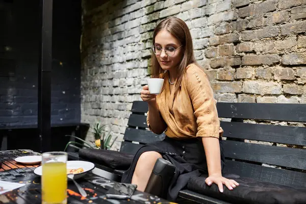 Eine junge Frau sitzt in einem gemütlichen Café, nippt an ihrem Kaffee und genießt den Moment, umarmt ihren pulsierenden Lebensstil mit einem künstlichen Glied. — Stockfoto