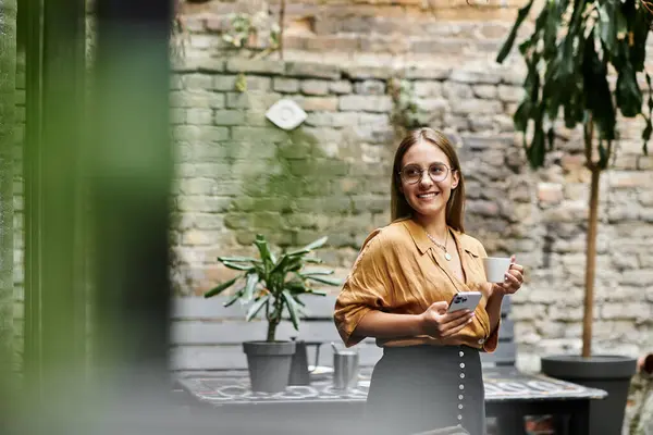 In un affascinante bar, una giovane donna tiene una tazza di caffè e sorride, mostrando il suo stile di vita vivace. — Foto stock