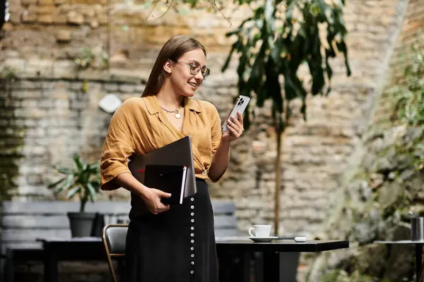 A young woman relaxes in a charming cafe, engaged in her phone — Stock Photo