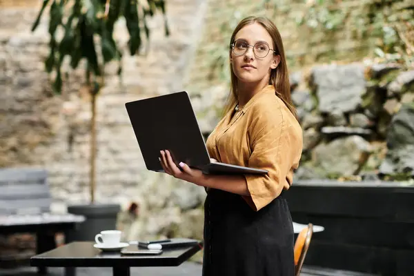 In un ambiente vivace caffè, una giovane donna si impegna con il suo computer portatile, mostrando la sua routine quotidiana. — Foto stock
