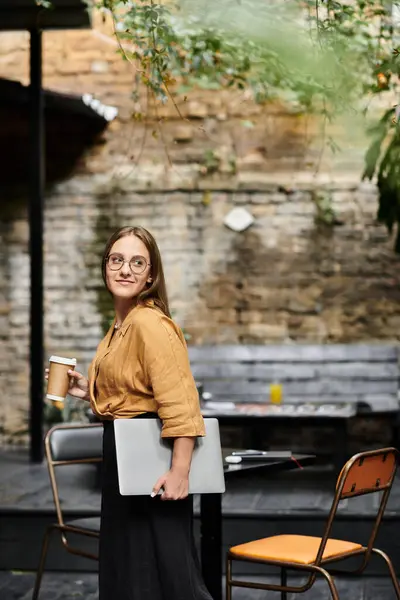 Una joven saborea su café en un acogedor café, abrazando una mezcla de trabajo y relajación. — Stock Photo