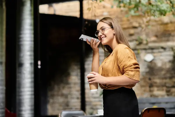 A young woman smiles while talking on her phone, savoring her coffee — Stock Photo