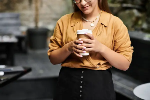 A young woman in a cozy cafe, savoring her coffee and showcasing her dynamic lifestyle — Stock Photo