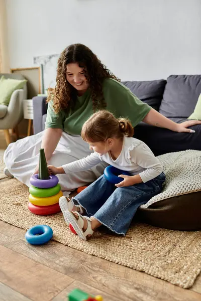 A mother enjoys quality time with her daughter, building a colorful stacking toy together. — Stock Photo