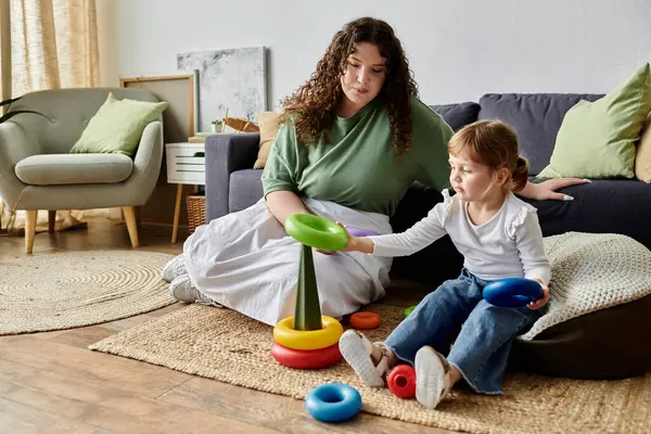 Una madre e una figlia si impegnano gioiosamente in giocoso impilamento di anelli colorati su un tappeto accogliente. — Foto stock